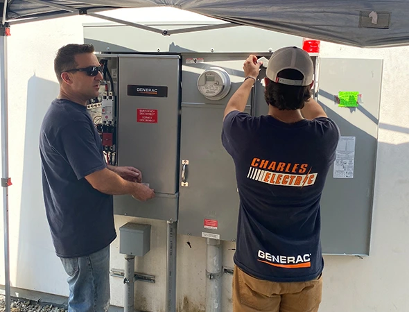 Two of our experts working together to install a large metal box for expert battery backup services.