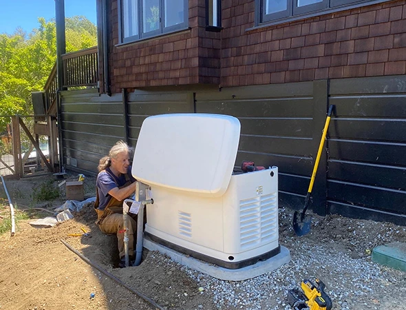 A technician working on the internal components of a white backup unit during a whole home generator installation.
