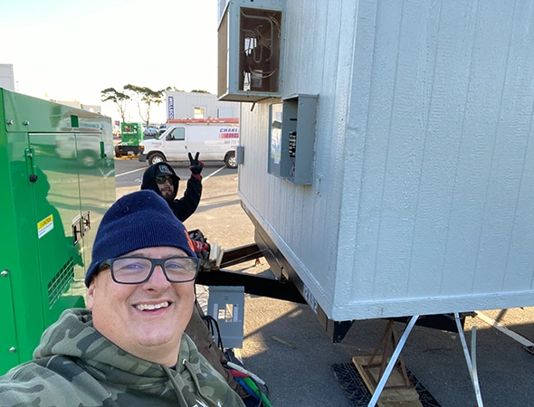 One of our friendly team members checking the exterior of a white hybrid unit under the Emerald Hills sun.