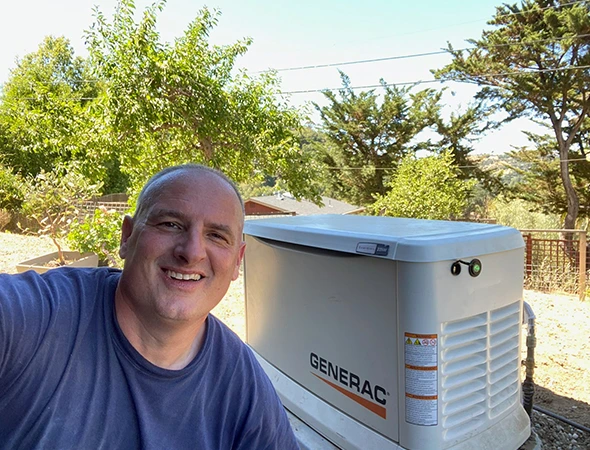 A smiling technician standing next to a high-quality Generac unit installed for a Hillsborough homeowner.