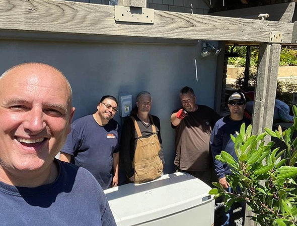 Our friendly crew members smiling while performing engine diagnostics on a residential unit in Los Altos.