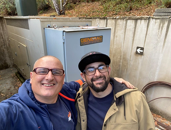 Our friendly pair of experts standing next to a new outdoor battery unit in Woodside.