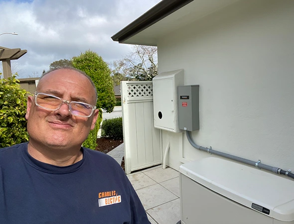 A technician smiling in front of a wall-mounted energy storage system at a Woodside home.